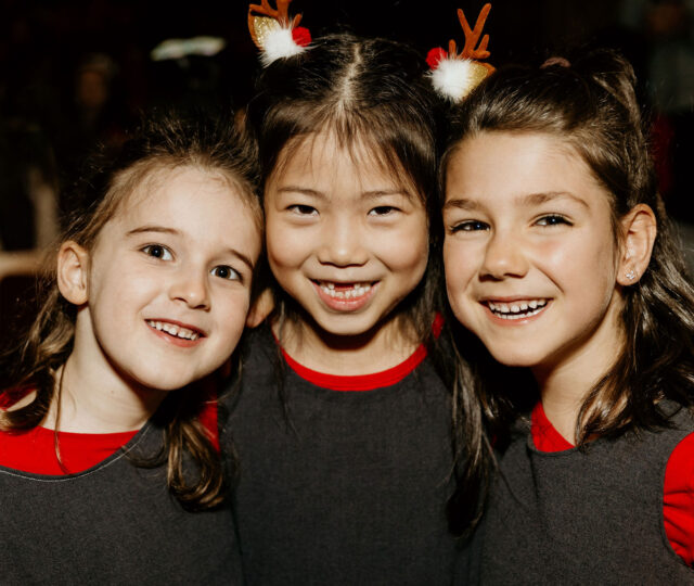 Three choristers from the childrens choirs smiling at a concert